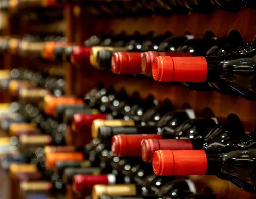 Rows of black red wine bottles sit along their wooden storage racks.