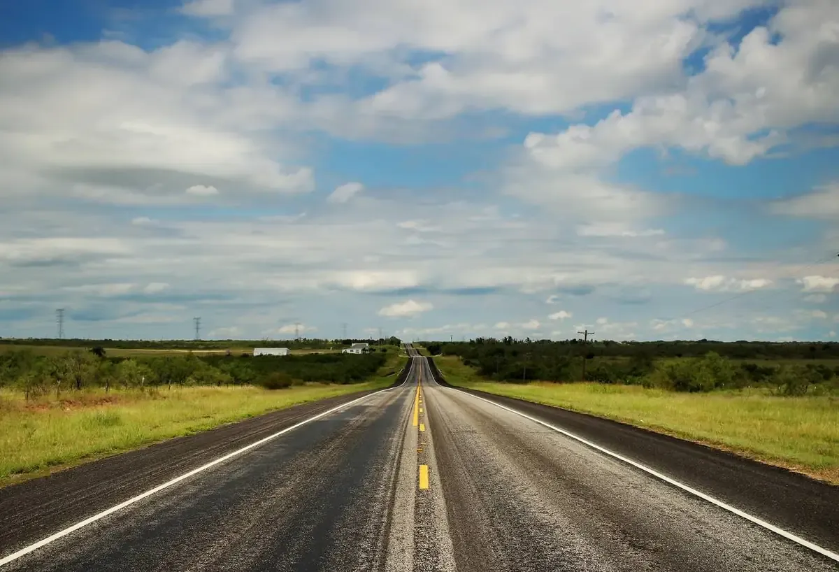 A long road stretching into the horizon down a Texas highway.