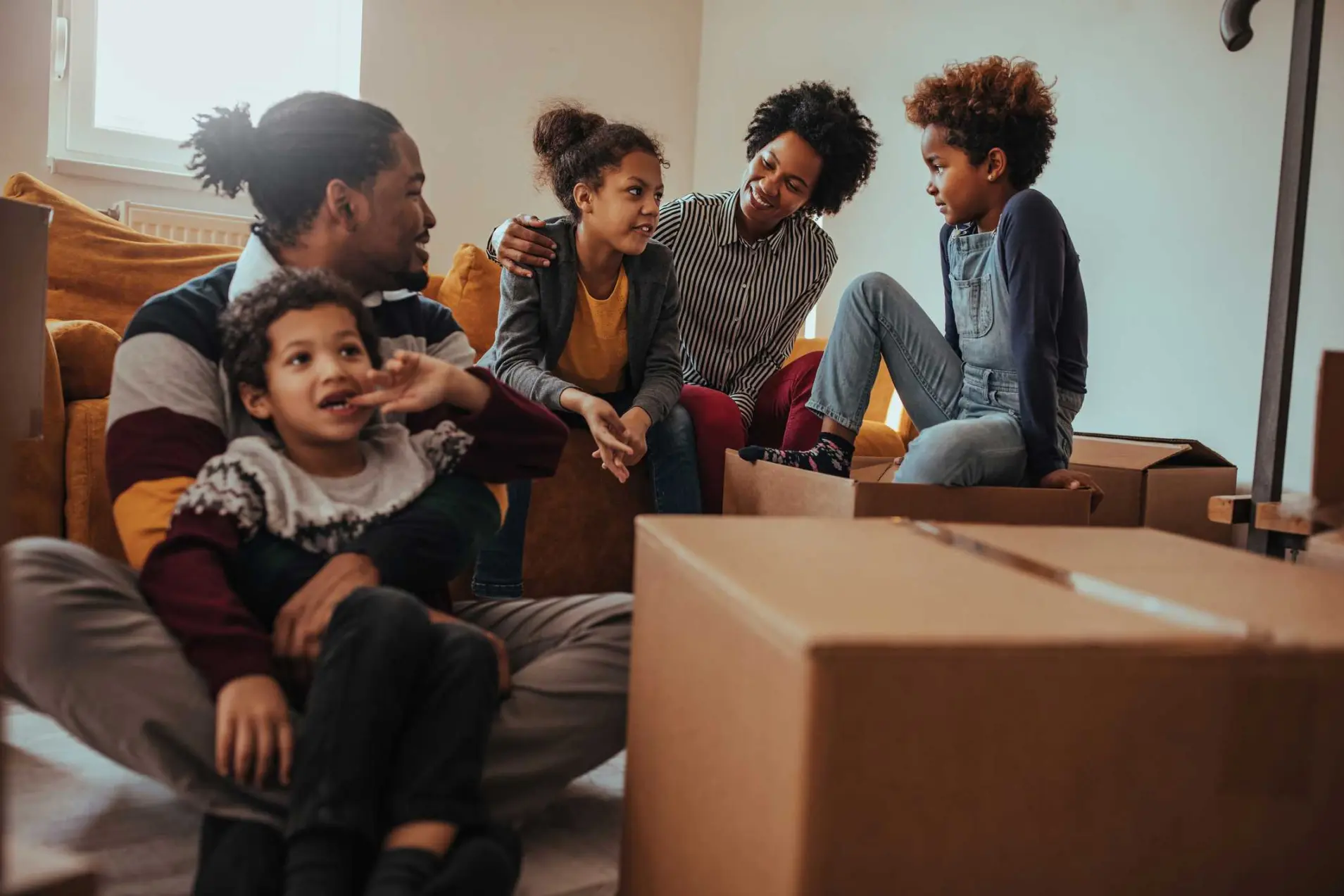 A happy family sitting on the floor of their apartment with boxes on moving day.