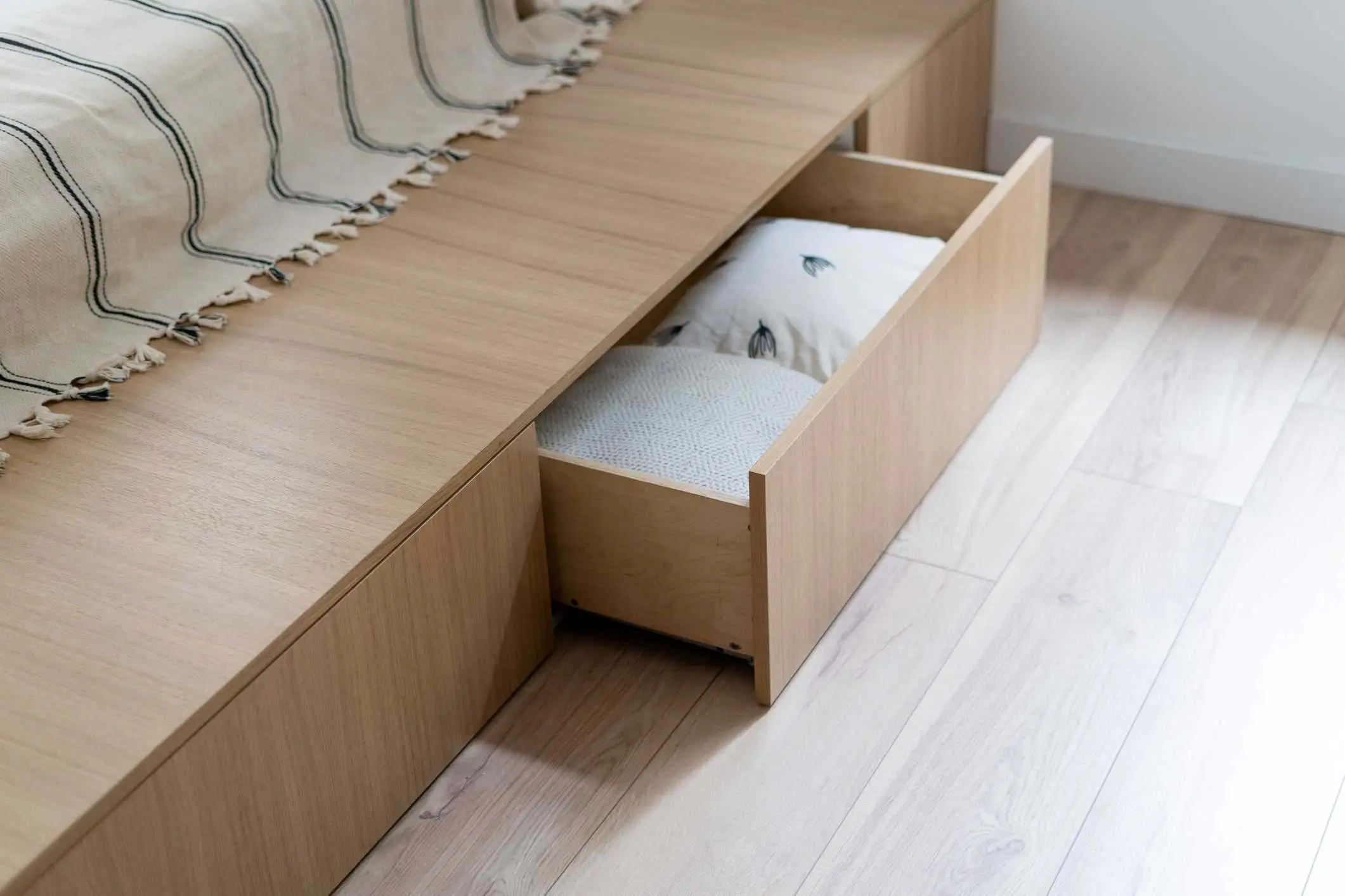 A drawer under a bed holds extra pillows as an under-bed storage solution. 