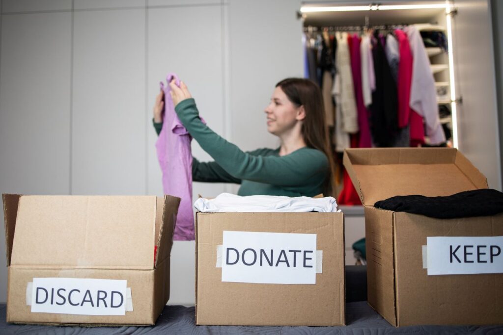 A woman organizing her clothes in “donate,” “discard,” and “keep” boxes.