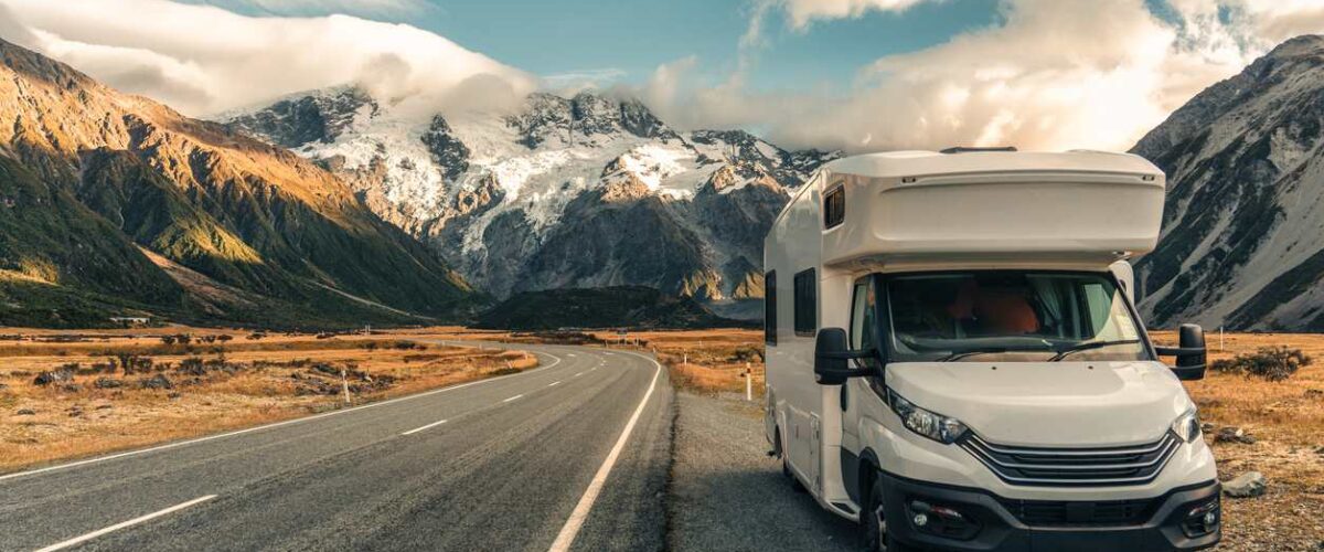 A camper parked on the roadside with a scenic view of mountains in the background.