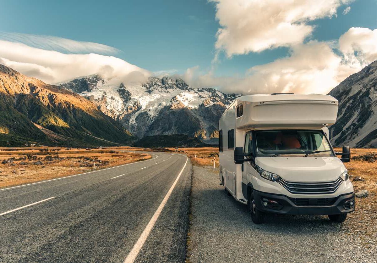 A camper parked on the roadside with a scenic view of mountains in the background.